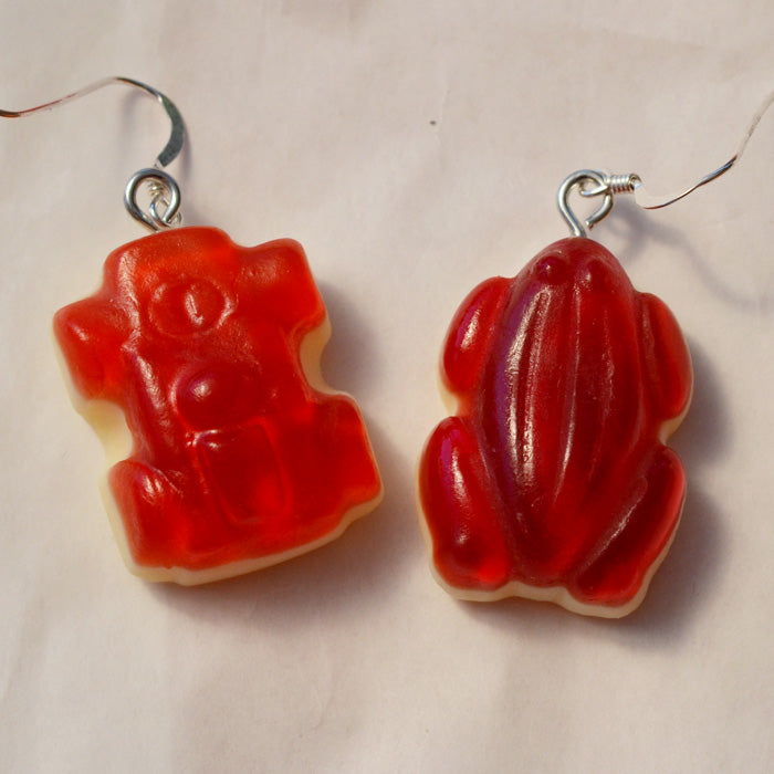 close up of red racing car and red frog lolly novelty earrings made from resin against a white background