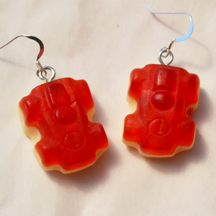close up of red racing car lolly novelty earrings made from resin on a white background