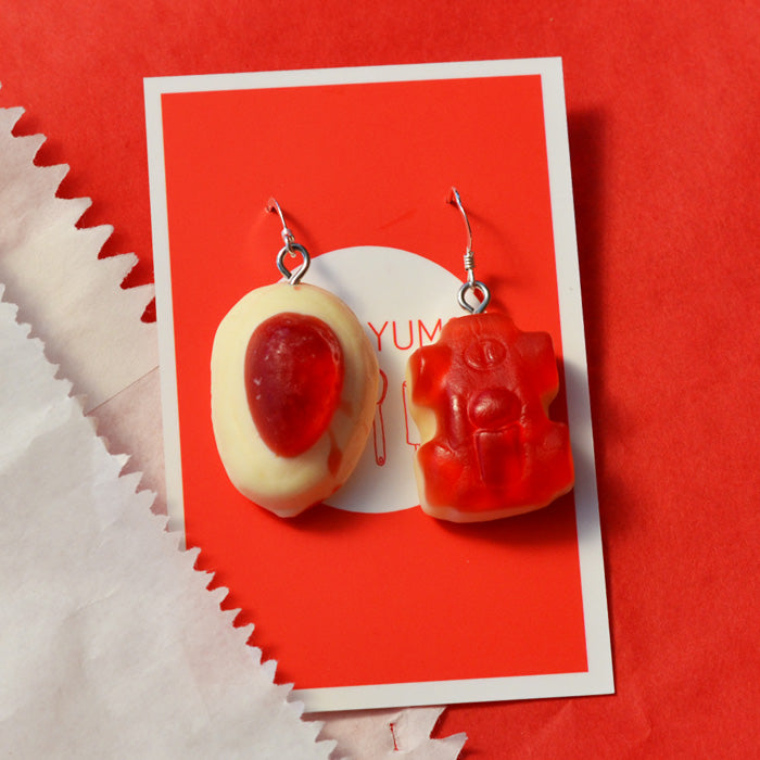red and white strawberry cream and racing car lolly novelty earrings made from resin against a red and white background