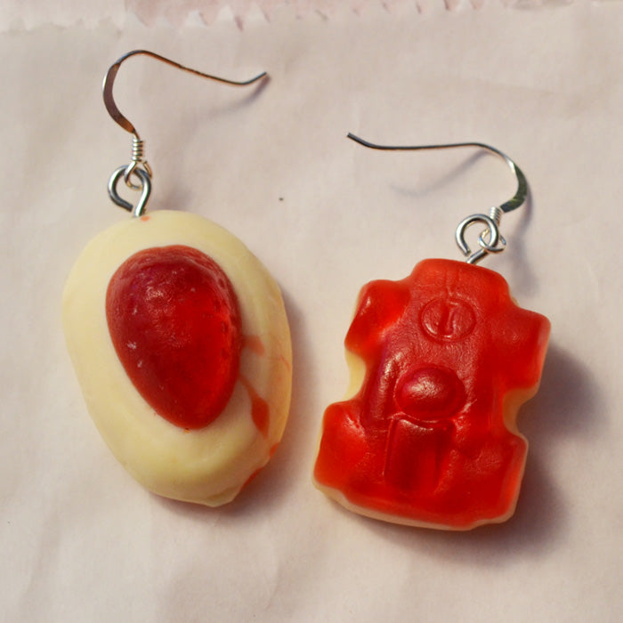 close up of red and white strawberry and cream and red racing car lolly novelty earrings made from resin against a white background