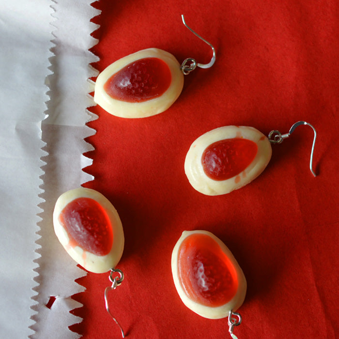 multiple red and white strawberry and cream lolly novelty earrings made from resin on a red and white background