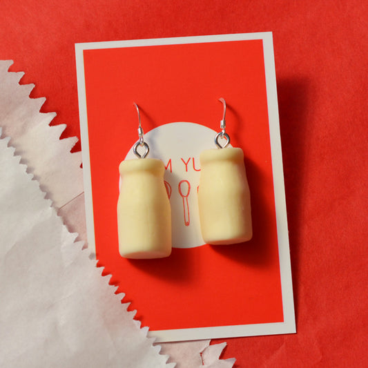 Milk bottle lolly novelty earrings made from resin on a white and red background