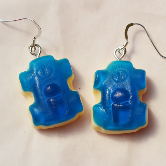 Close up of Blue and white racing car lolly novelty earrings against a white background