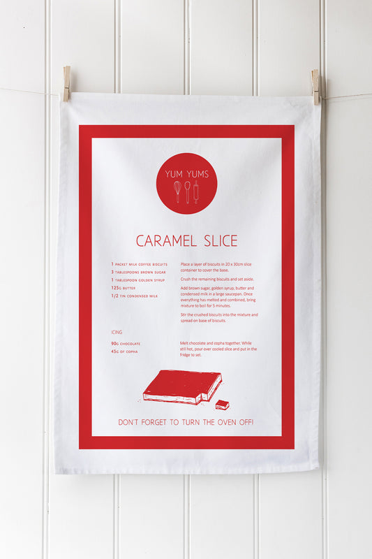 A white tea towel with a red border. A caramel slice recipe in red text below the Yum Yums logo (red circle and white text with drawing of a whisk, rolling pin and spoon) Drawing of a caramel slice with a peice cut out of it.